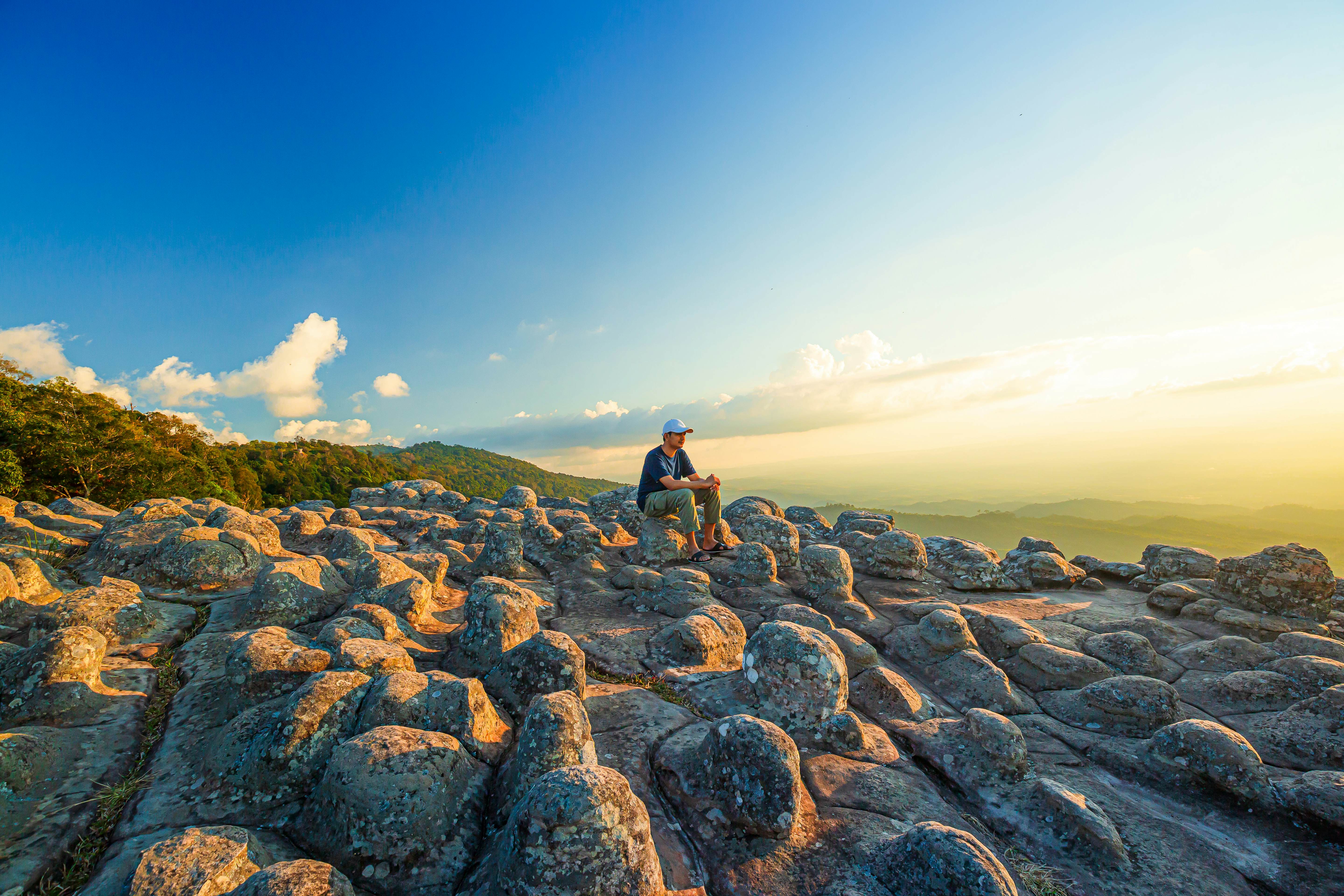 Lan Hin Pum National Park,Male tourist and mountain view,Young man with backpack sitting on rock looking into the landscape. Listening to the silence. Beautiful moment the miracle of nature.